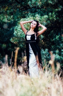 Zarif çekici esmer model iğne yapraklı Park siyah elbise poz