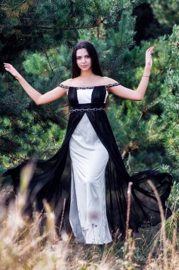 Zarif çekici esmer model iğne yapraklı Park siyah elbise poz