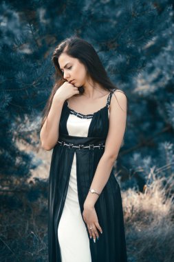 Zarif çekici esmer model iğne yapraklı Park siyah elbise poz