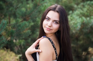 Zarif çekici esmer model iğne yapraklı Park siyah elbise poz