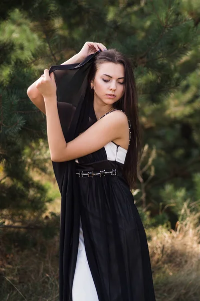 Sierlijke charmante brunette model poseren in zwarte jurk in naaldhout park — Stockfoto