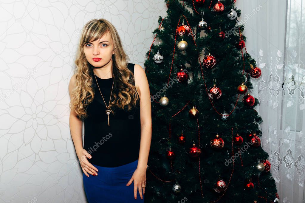 Beautiful blonde near a Christmas tree.