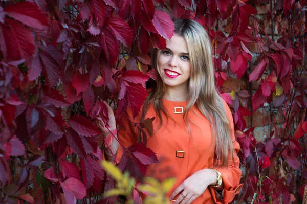 Gülümseyen kız kırmızı ile duvara yaslanmış yapraklar