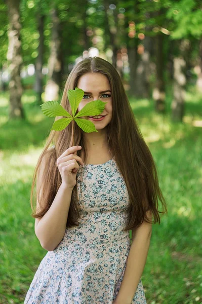 ブルネットの少女隠れ笑顔の葉で. — ストック写真