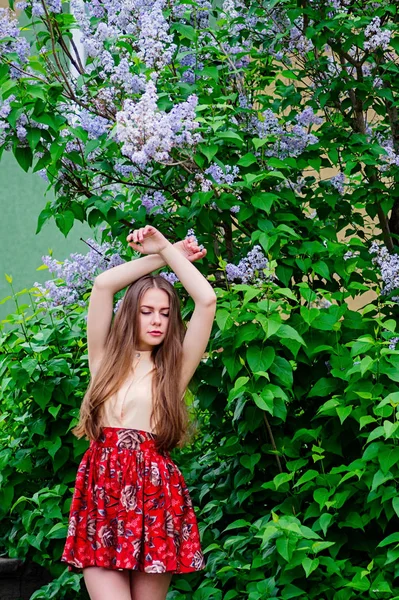 ブルーミング ライラックに対して庭でポーズかわいい女の子. — ストック写真