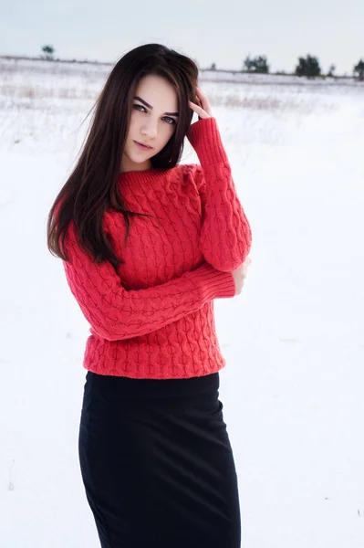 Девушка в снежном дворе зимой в красном вязаном свитере . — стоковое фото