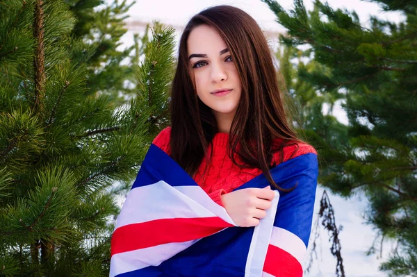 Jovem com uma bandeira britânica em uma floresta de inverno no inverno . — Fotografia de Stock