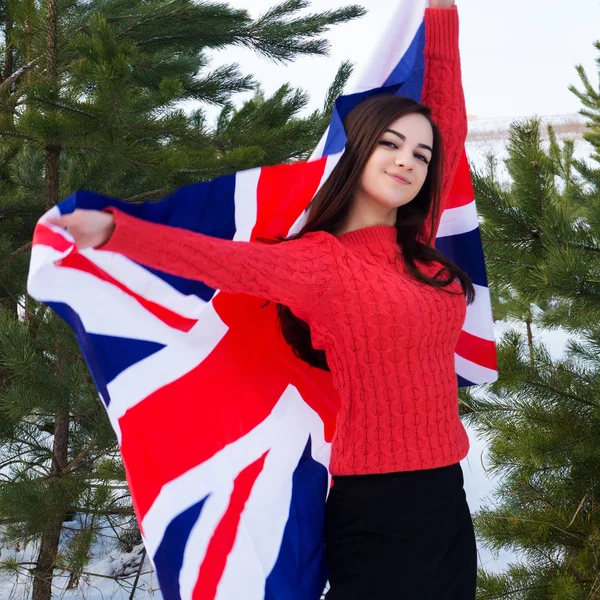 Jovem com uma bandeira britânica em uma floresta de inverno no inverno . — Fotografia de Stock