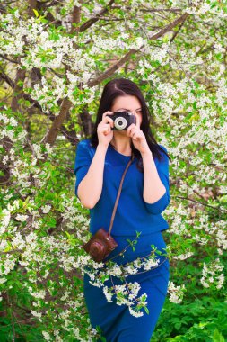 Retro kamera mavi bir elbise fotoğraf çekimi ile genç bir kadın