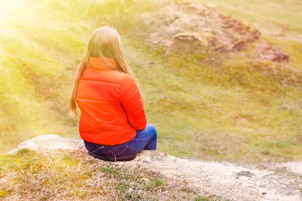 La ragazza in giacca rossa siede sulla cima della montagna . — Foto Stock