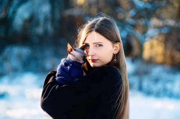 Schöne junge Mädchen mit Katze Rasse Don Sphinx auf ihren Händen im Winter im Park. — Stockfoto
