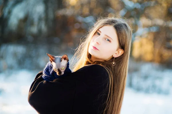 美しいです若いです女の子とともに猫品種ドンsphinx上の彼女の手で冬に公園. — ストック写真