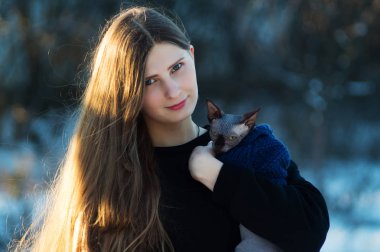 Genç güzel kız kollarını onu kedi ile. Parlak bir günde kış parkta. Kedi doğurmak İsviçre