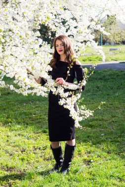 Moda model siyah şık elbise giymiş. Bir çiçek açan içinde ayakta Parkı kiraladım. beyaz bir Semazen dal üzerinde tutar.