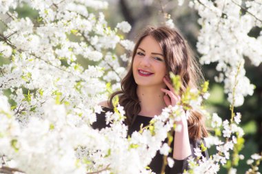 Moda model siyah şık elbise giymiş. Bir çiçek açan içinde ayakta Parkı kiraladım. portre. Parlak bahar çiçek portresi