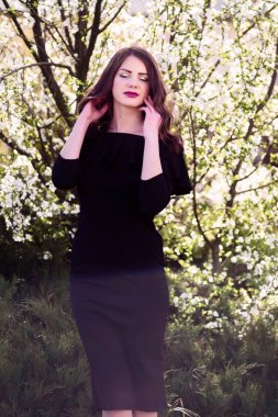 siyah elbise modeli. Sıcak güneşli parkta. Dikey fotoğraf. Yıl boyun etrafında.