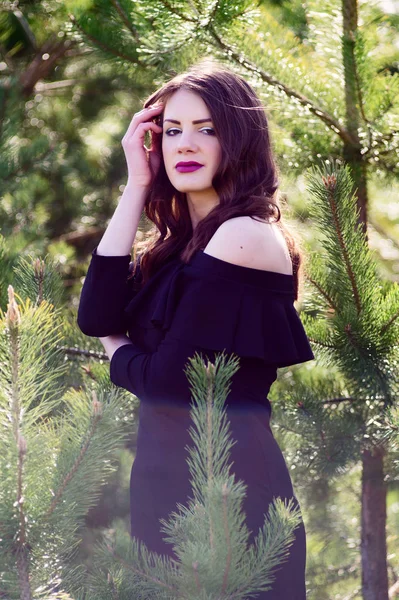 Fashion model in black dress in the summer dressed in a black dress. Green forest.