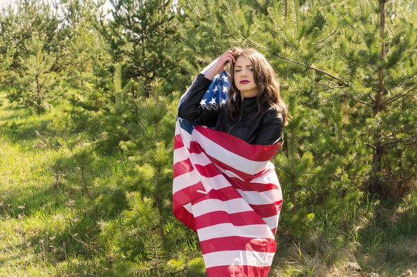A young beautiful woman with a flag of the United States of America Wrapped in a flag copy space