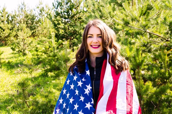 A young beautiful woman with a flag of the United States of America.Smiles