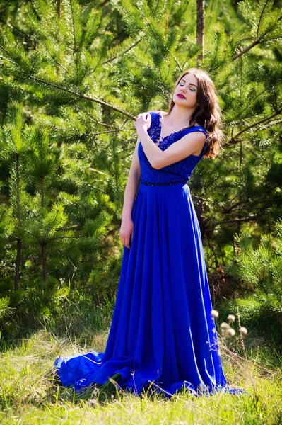 Beautiful fashion model in a dress in a green park in the summer. Closed eyes