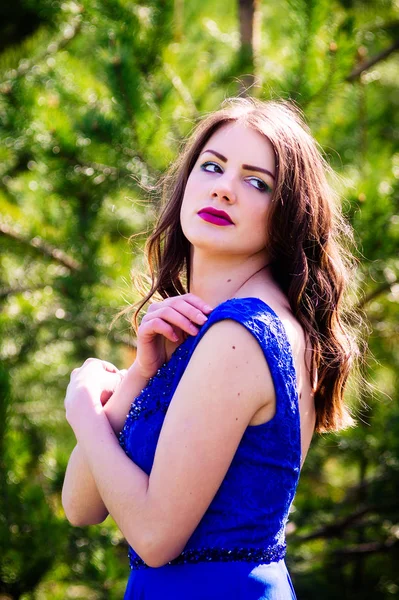 Beautiful fashion model in a dress in a green park in the summer. Blue dress.