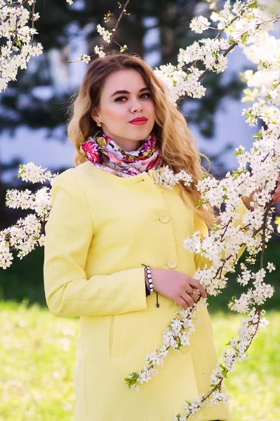 Een Jonge Vrouw Gekleed Een Modieuze Gele Vacht Een Bloeiende — Stockfoto