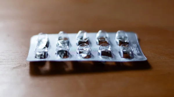 Emballage vierge de médicaments repose sur une table en bois . — Photo