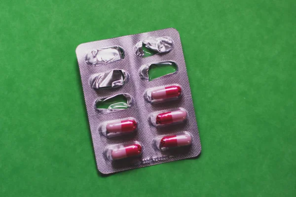 Pack de píldoras rojas blancas sobre fondo verde . —  Fotos de Stock