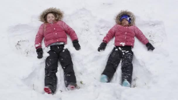 Dos Hermanas Haciendo Ángeles Nieve Nieve Fresca Mientras Sonríen — Vídeo de stock