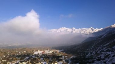 Utah 'ta mavi bir kuş gününde bulutların altındaki evlerin manzarası dağlara doğru dönüyor..