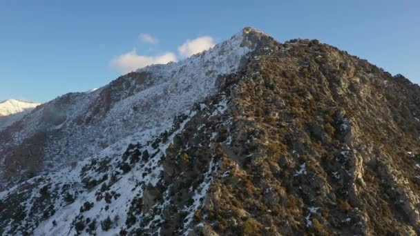 日陰の側に雪のある山の眺めは 太陽が日当たりの良い側を溶かしながら山頂を一周します — ストック動画