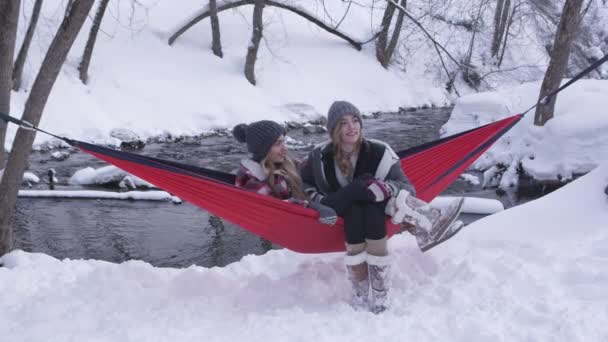 Irmãs Gêmeas Sentadas Fora Neve Rede Conversando Lado Pequeno Rio — Vídeo de Stock