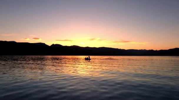 ヘブヘン湖の夕暮れ時に人々が魚として湖の上に小さなボートに向かって空中飛行 — ストック動画