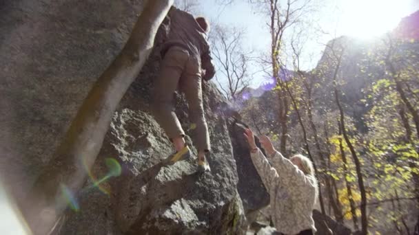 Hombre Escalando Roca Como Mujer Sostiene Los Brazos Hacia Arriba — Vídeos de Stock