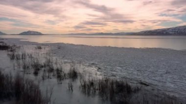 Utah 'ta kış boyunca donmuş gölün kıyılarında uçarak gün batımına doğru..