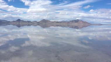 Bonneville Tuz Düzlükleri 'nin üzerindeki bulutların yansıması gölün üzerinde uçarken tuzun altındaki çatlakları görüyor..