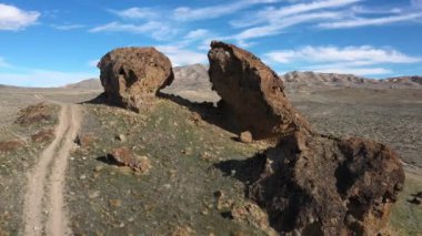 Utah Çölü 'ndeki iki büyük kayanın arasında toprak yol boyunca uçarak manzaranın içinden geçen yolu izleyerek..