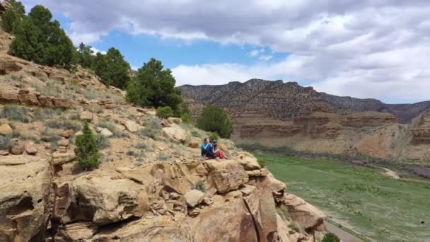 Dwie Kobiety Siedzące Skraju Urwiska Patrzące Przez Dolinę Obracając Się — Wideo stockowe