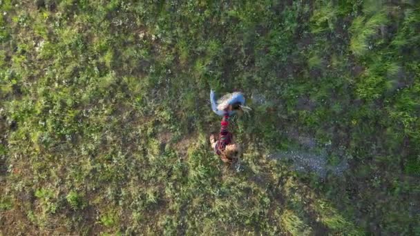 Vue aérienne montante regardant deux filles danser dans une forêt qui tourne lentement tout en grimpant haut au-dessus des arbres .