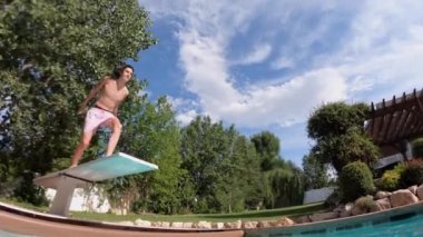 Yüzme havuzuna dalan genç bir adamın yan görüntüsü.