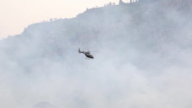 Helikopter, itfaiyecilerin ilerleyişini görmek için vahşi ateşin üzerinde uçuyor ve yanan yeni bölgeleri tespit ediyor..