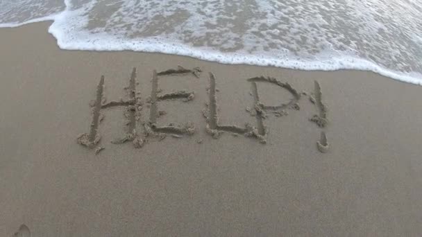 波が海に戻る時に 海水がそれを退色する際に 浜辺で砂の中に書かれた助け — ストック動画