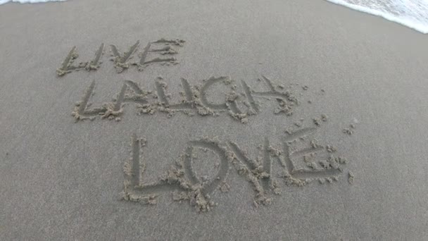 Live Laugh Love Written Sand Beach Wave Rolls Shore Water — Stock Video