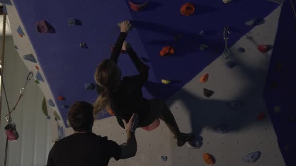 Man Spotting Woman She Free Climbs Wall Using Her Strength — Stock Video