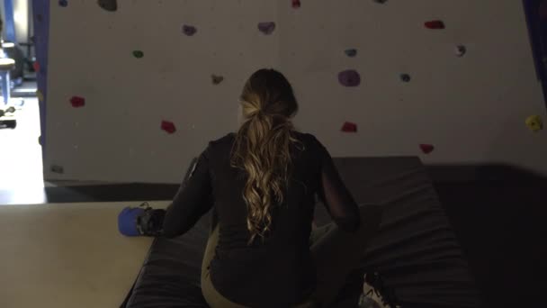 女人穿着鞋子坐在攀岩墙前的撞车垫上 — 图库视频影像
