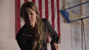 Amerikan Bayrağı 'nın önünde elinde balyozla kameraya bakan genç bir kadın..