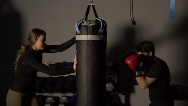 Homem Boxe Com Saco Perfuração Como Mulher Mantém Ainda Para — Vídeo de Stock