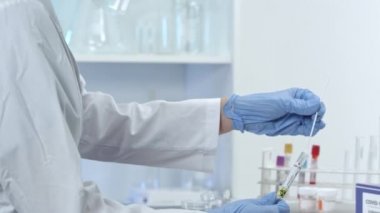 Kadın laboratuar teknisyeni tüp içine çubuk testi ekliyor ve Coronavirus testi sırasında tıbbi tesisi mühürlüyor..