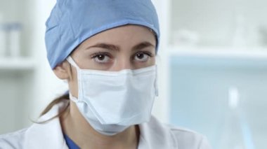 Tıbbi laboratuarda yüz maskesi takan kadın hemşire Covid-19 test kiti tutuyor..