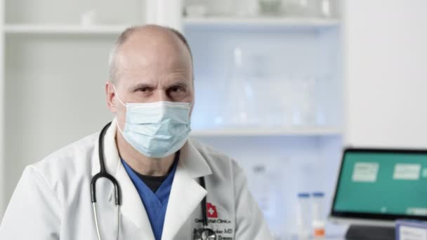 Médico Usando Máscara Facial Girando Olhando Para Câmera Durante Surto — Vídeo de Stock